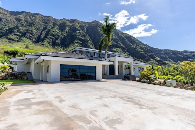view of front of property with an attached garage, driveway, a mountain view, and stucco siding