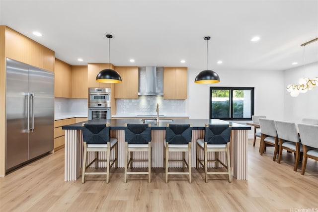 kitchen featuring wall chimney range hood, appliances with stainless steel finishes, modern cabinets, and light wood finished floors