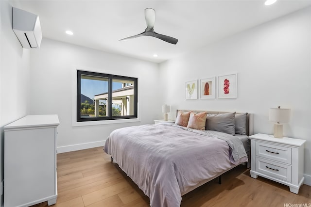 bedroom featuring recessed lighting, baseboards, light wood-type flooring, and a wall mounted air conditioner
