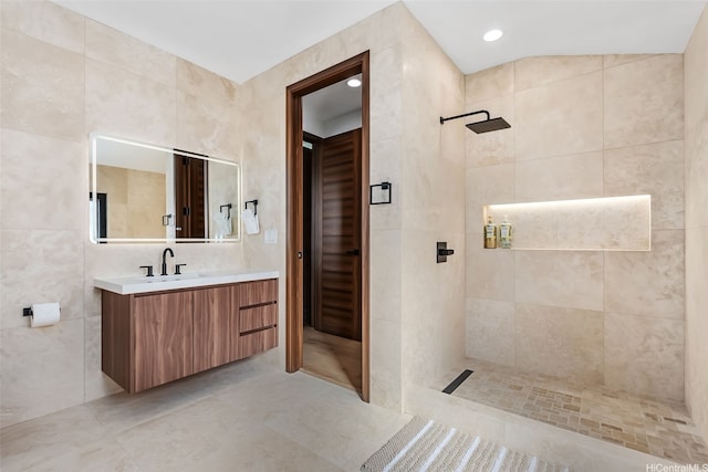 bathroom with vanity, tile patterned flooring, tile walls, recessed lighting, and a walk in shower