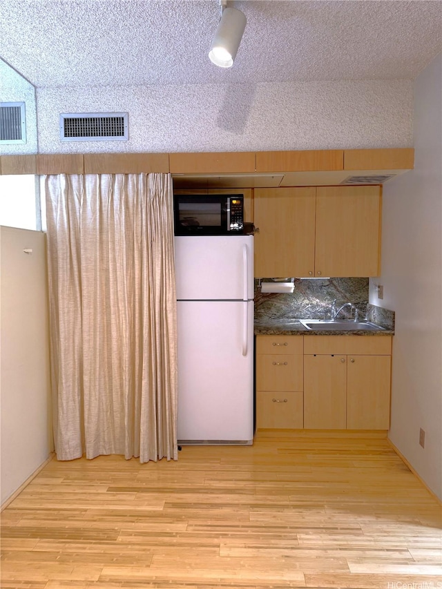 1188 Bishop St Unit 701, Honolulu, HI 96813 - kitchen featuring black microwave, dark countertops, light wood-type flooring, a sink, and freestanding refrigerator