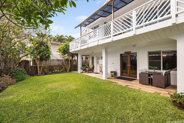 view of yard featuring french doors, fence, a patio, and a balcony