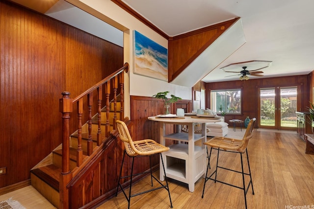 dining space with wooden walls, a ceiling fan, stairs, and wood finished floors
