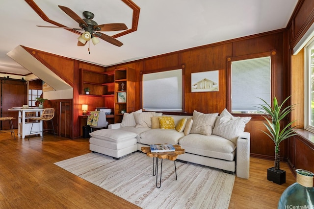 living room featuring a healthy amount of sunlight, wood walls, and wood finished floors