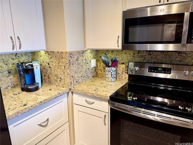 kitchen with white cabinetry, appliances with stainless steel finishes, light stone countertops, and tasteful backsplash