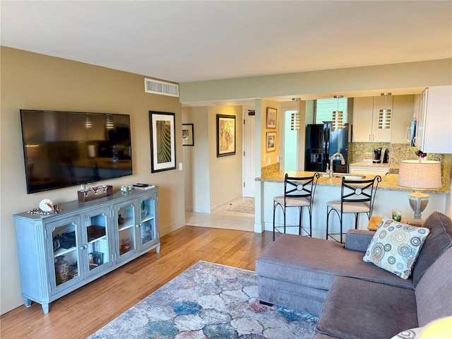 living area with baseboards, visible vents, and light wood-style floors