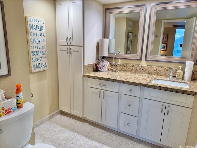 bathroom with toilet, baseboards, visible vents, and vanity