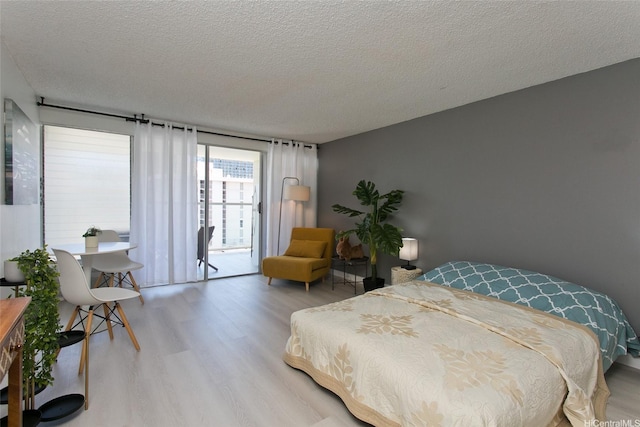 bedroom featuring access to outside, a textured ceiling, and wood finished floors