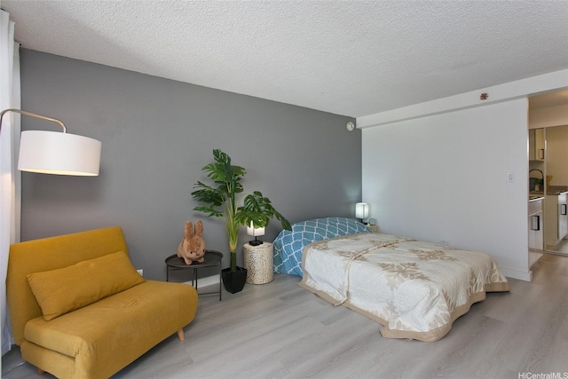 bedroom with a textured ceiling and wood finished floors