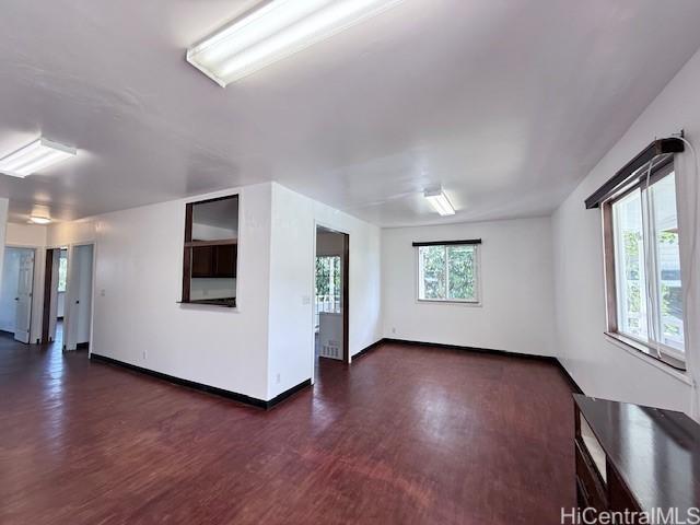 spare room featuring baseboards and dark wood-style flooring