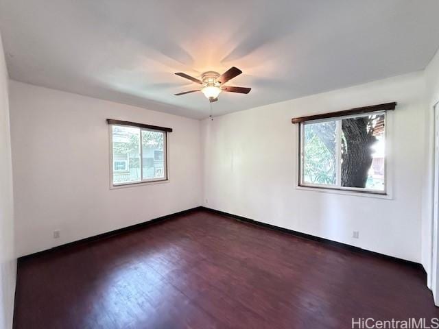 spare room with a wealth of natural light, dark wood finished floors, and ceiling fan