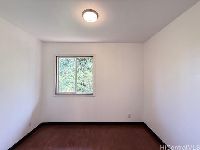 unfurnished room featuring baseboards and dark wood-style flooring