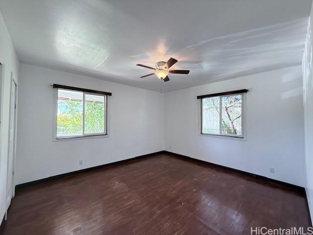 unfurnished room with baseboards, a healthy amount of sunlight, dark wood finished floors, and ceiling fan
