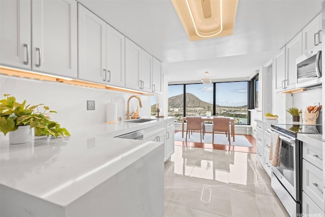 250 Kawaihae St Unit 18D, Honolulu, HI 96825 - kitchen featuring appliances with stainless steel finishes, light countertops, white cabinetry, a mountain view, and expansive windows