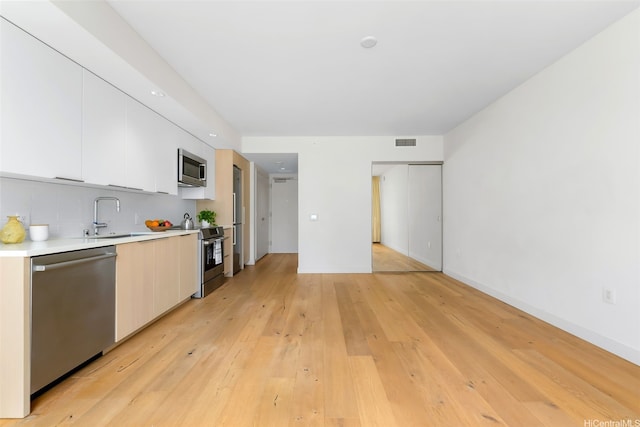 1001 Queen St Unit 1010, Honolulu, HI 96814 - kitchen with appliances with stainless steel finishes, modern cabinets, light countertops, white cabinetry, and light wood-style flooring
