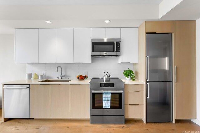 1001 Queen St Unit 1010, Honolulu, HI 96814 - kitchen with stainless steel appliances, light countertops, modern cabinets, tasteful backsplash, and light wood-style flooring