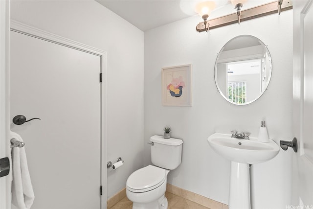 bathroom with toilet, baseboards, and tile patterned flooring