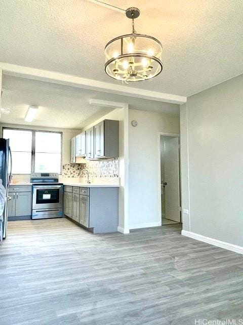 kitchen with stainless steel electric range, gray cabinetry, and an inviting chandelier