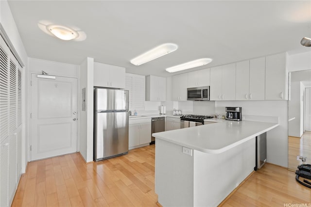 2895 Kalakaua Ave Unit 1202, Honolulu, HI 96815 - kitchen featuring appliances with stainless steel finishes, a peninsula, light countertops, light wood-type flooring, and white cabinetry