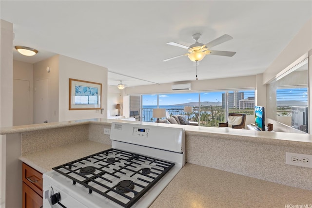 2161 Kalia Rd Unit 1112, Honolulu, HI 96815 - kitchen with white range with gas stovetop, an AC wall unit, ceiling fan, open floor plan, and light countertops