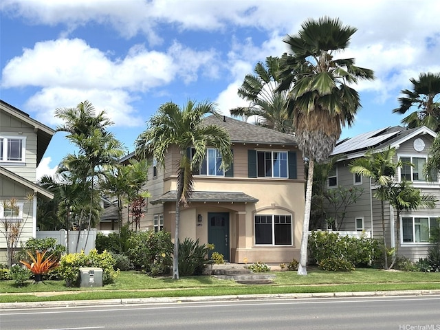view of front of home with a shingled roof, stucco siding, and fence