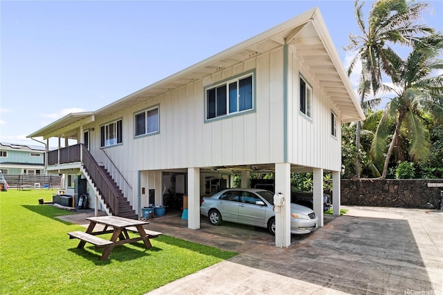 rear view of property with fence, stairway, a carport, a yard, and driveway