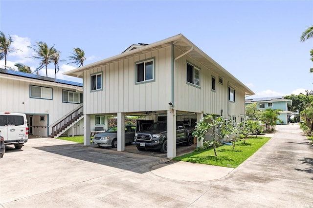 view of front facade featuring stairs, concrete driveway, board and batten siding, and a carport