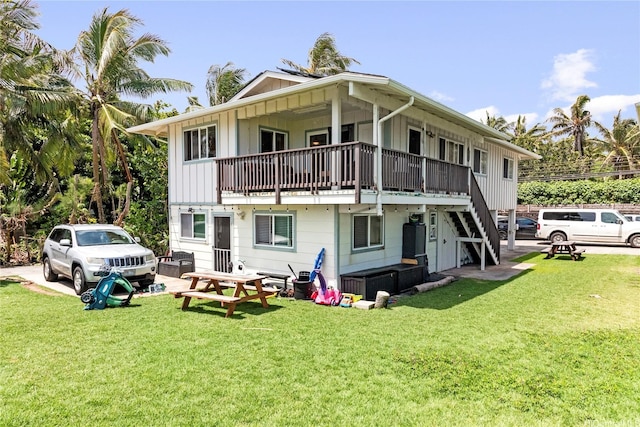 back of property with a lawn, board and batten siding, and stairway