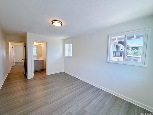 unfurnished bedroom featuring wood finished floors, baseboards, and a sink