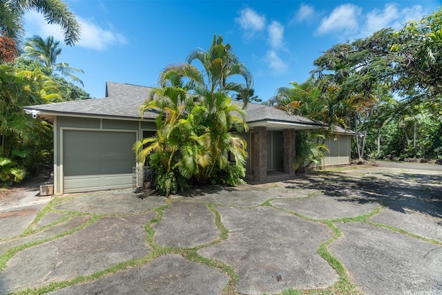 view of front facade featuring concrete driveway, roof with shingles, and a garage