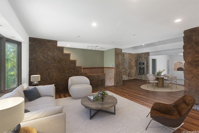interior space with stairway, a stone fireplace, and wood finished floors