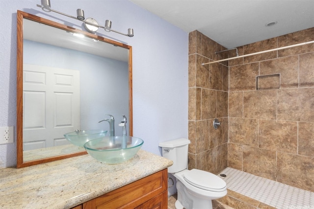 bathroom featuring vanity, toilet, and tiled shower