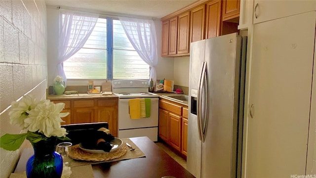 kitchen with light countertops, stainless steel fridge, a sink, and electric stove