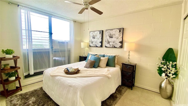 bedroom featuring concrete block wall, a ceiling fan, and a textured ceiling