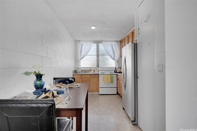 98-114 Lipoa Pl Unit 209, Aiea, HI 96701 - kitchen featuring white range with electric cooktop, freestanding refrigerator, light countertops, concrete block wall, and light brown cabinets