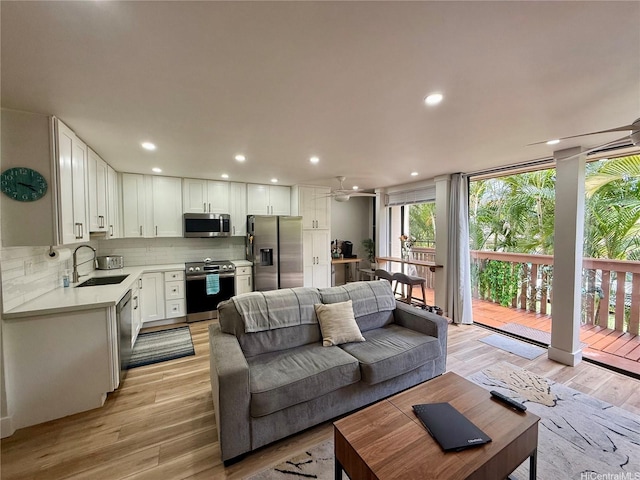 living room with light wood-style flooring, a ceiling fan, and recessed lighting