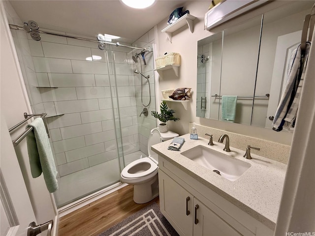 full bath with a stall shower, vanity, toilet, and wood finished floors