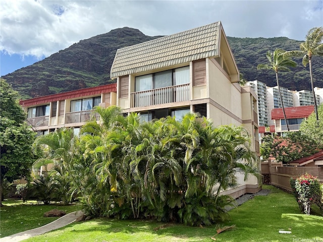 exterior space featuring a mountain view, a tile roof, and a front yard