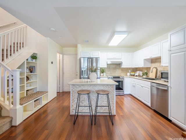 91-2067 Kaioli St Unit 503, Ewa Beach, HI 96706 - kitchen featuring appliances with stainless steel finishes, under cabinet range hood, a sink, dark wood-style floors, and white cabinets