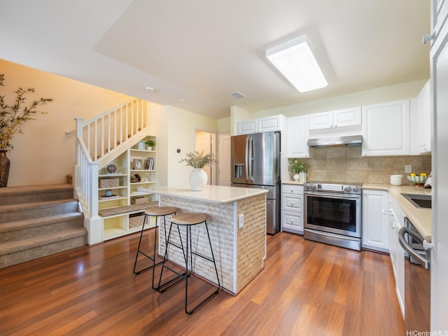 91-2067 Kaioli St Unit 503, Ewa Beach, HI 96706 - kitchen with stainless steel appliances, under cabinet range hood, a breakfast bar, dark wood-style flooring, and light countertops