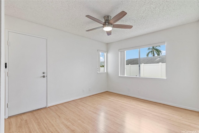 spare room with wood finished floors, a textured ceiling, ceiling fan, and baseboards