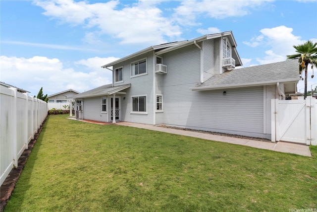 back of house featuring a gate, a patio area, a wall unit AC, and roof with shingles