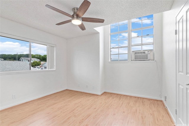 empty room with wood finished floors, ceiling fan, cooling unit, baseboards, and a textured ceiling