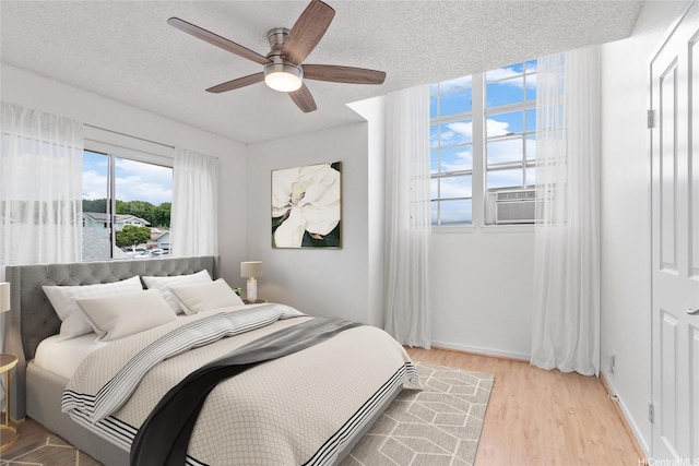bedroom featuring light wood-type flooring, ceiling fan, and a textured ceiling