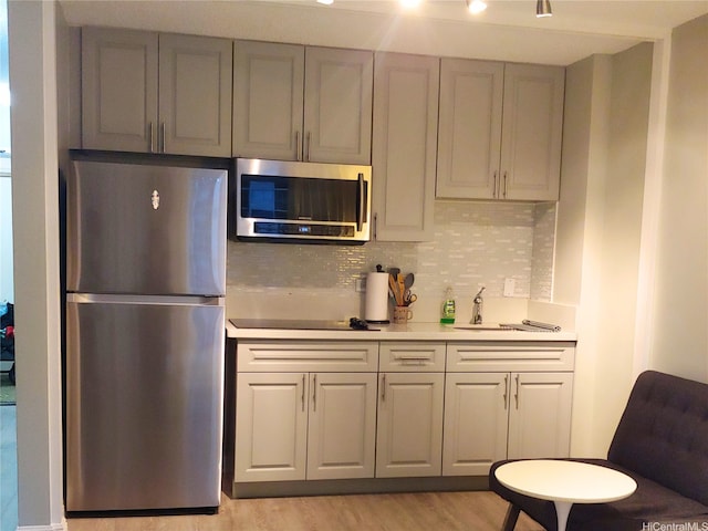 2345 Ala Wai Blvd Unit 1010, Honolulu, HI 96815 - kitchen with stainless steel appliances, a sink, light countertops, tasteful backsplash, and light wood-type flooring