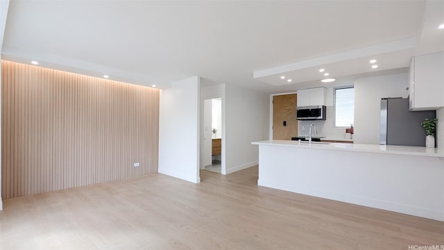 unfurnished living room with light wood-style floors, baseboards, a sink, and recessed lighting