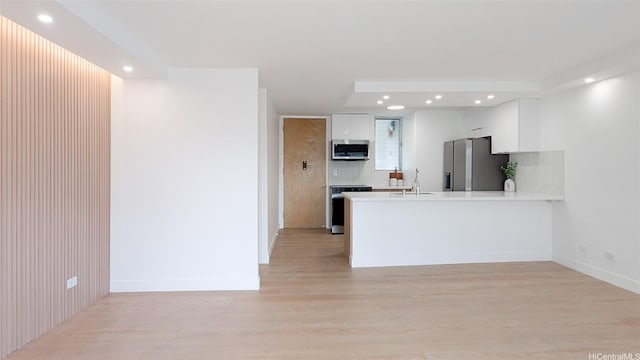 kitchen featuring a peninsula, stainless steel appliances, white cabinetry, and recessed lighting