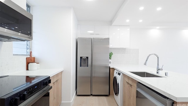 kitchen with a sink, washer / dryer, recessed lighting, modern cabinets, and appliances with stainless steel finishes