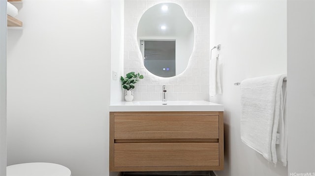 bathroom with toilet, decorative backsplash, and vanity