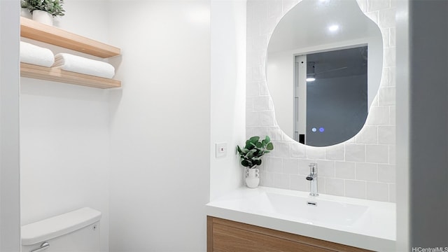 bathroom featuring toilet, vanity, and backsplash
